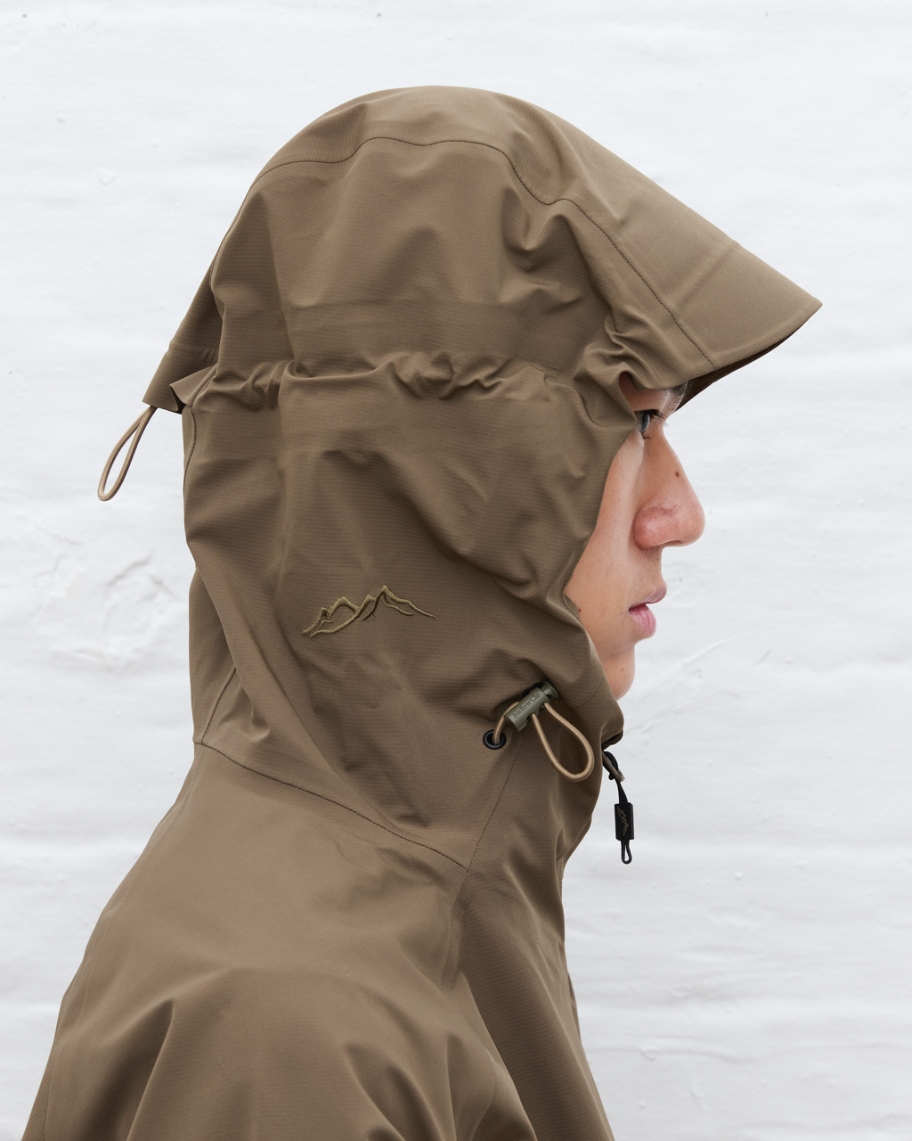 Person wearing a brown hooded jacket against a white background