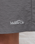 Gray shorts with 'Mellow Clo' logo on a close-up of fabric texture.