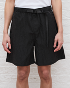 Person wearing black shorts with a belt on a light background